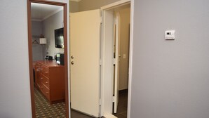 A hotel room with a wooden dresser, a television, and a mirror. - Econo Lodge Brockport (Brockport)