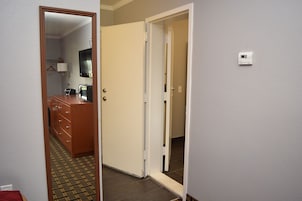 Una habitación de hotel con un aparador de madera, un televisor y un espejo.