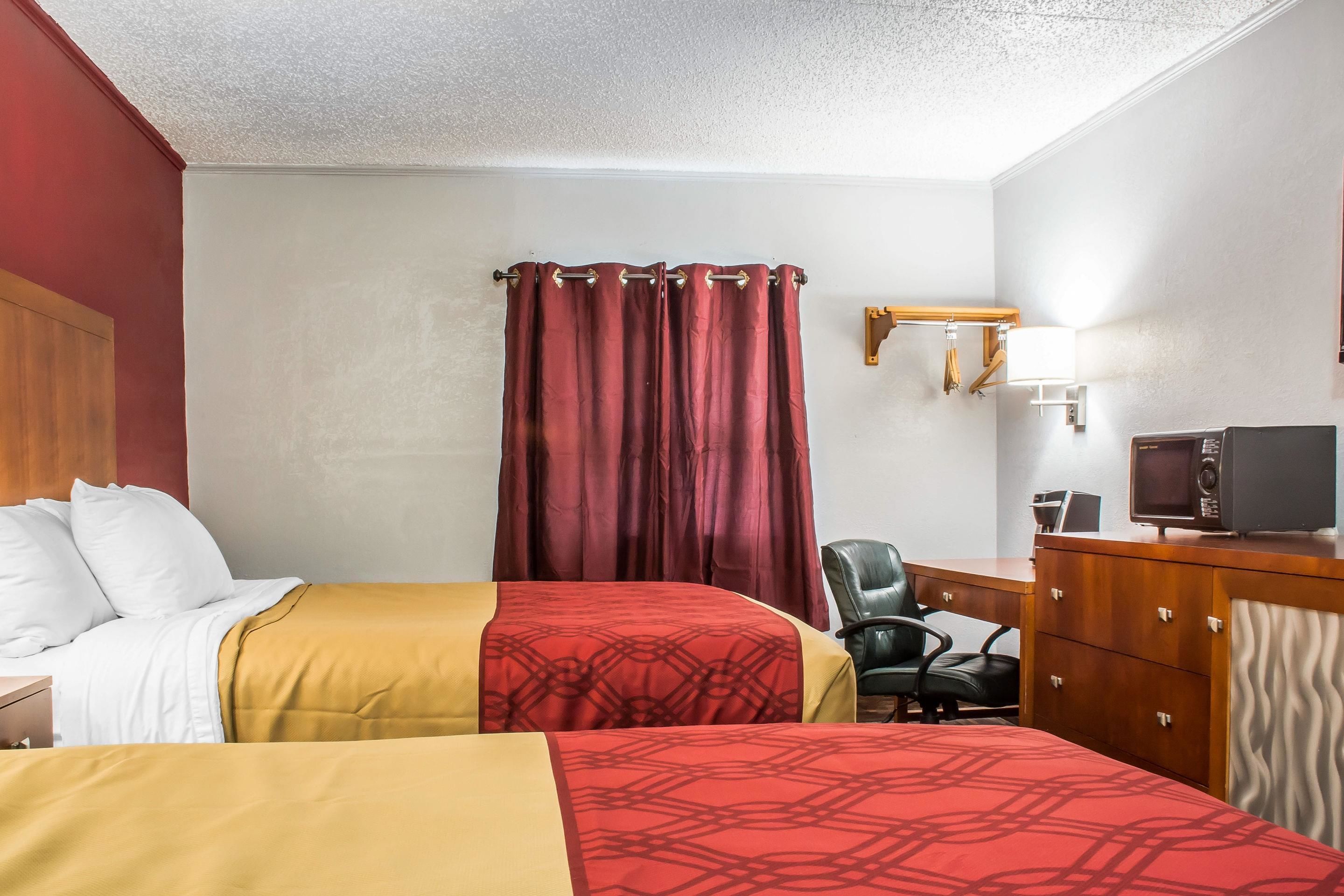 A hotel room with two beds, a desk with a computer, a chair, and a TV.