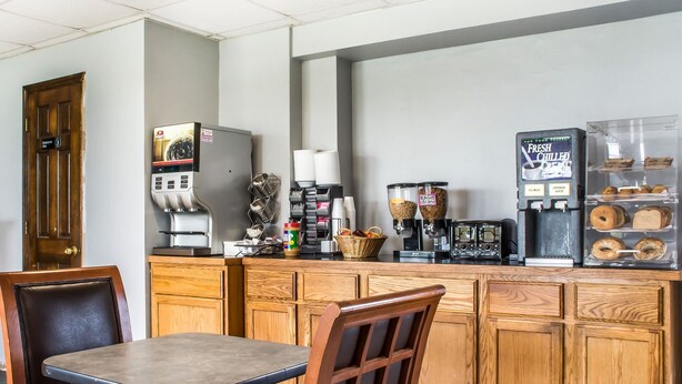 A kitchen area with wooden cabinets, a coffee machine, and a refrigerator. - Econo Lodge Brockport (Brockport)