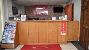 A reception desk with a red carpet, a stone wall, and a sign for EconoLodge in Brockport, NY. - Econo Lodge Brockport (Brockport)