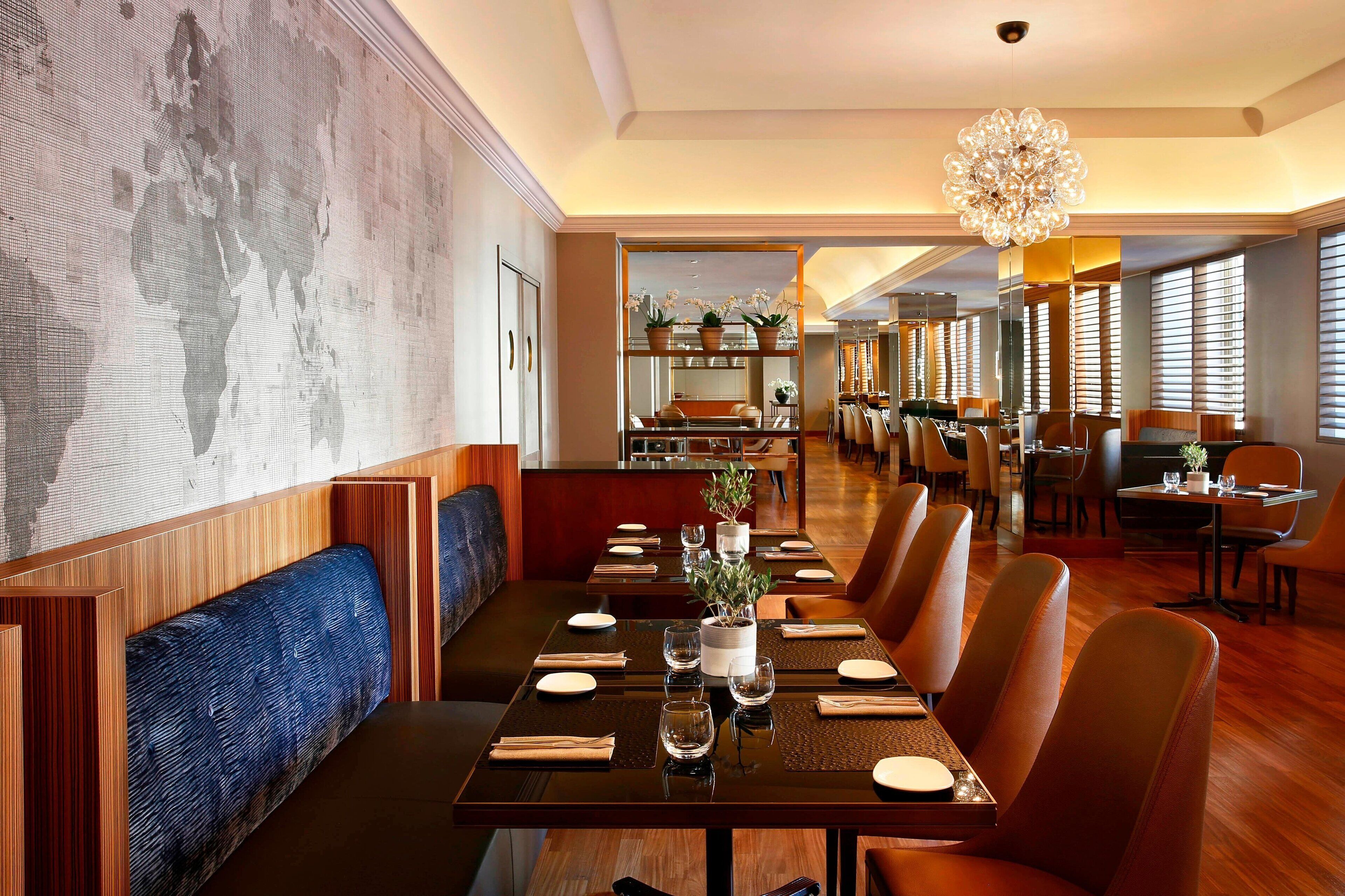 A restaurant with a long table set for dining, wooden paneling, and a large world map on the wall.