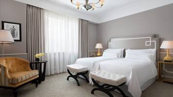 Una camera d'albergo con un letto grande, due comodini con lampade, una sedia e un tavolino con un vaso di fiori.