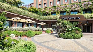 The Westin hotel with a courtyard featuring outdoor seating, a brick facade, and lush greenery. - The Westin Palace, Milan (Milan)