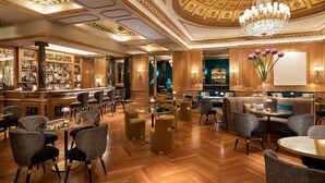 Eine luxuriöse Hotelhalle mit Bar, Sitzbereichen und einem prächtigen Kronleuchter.