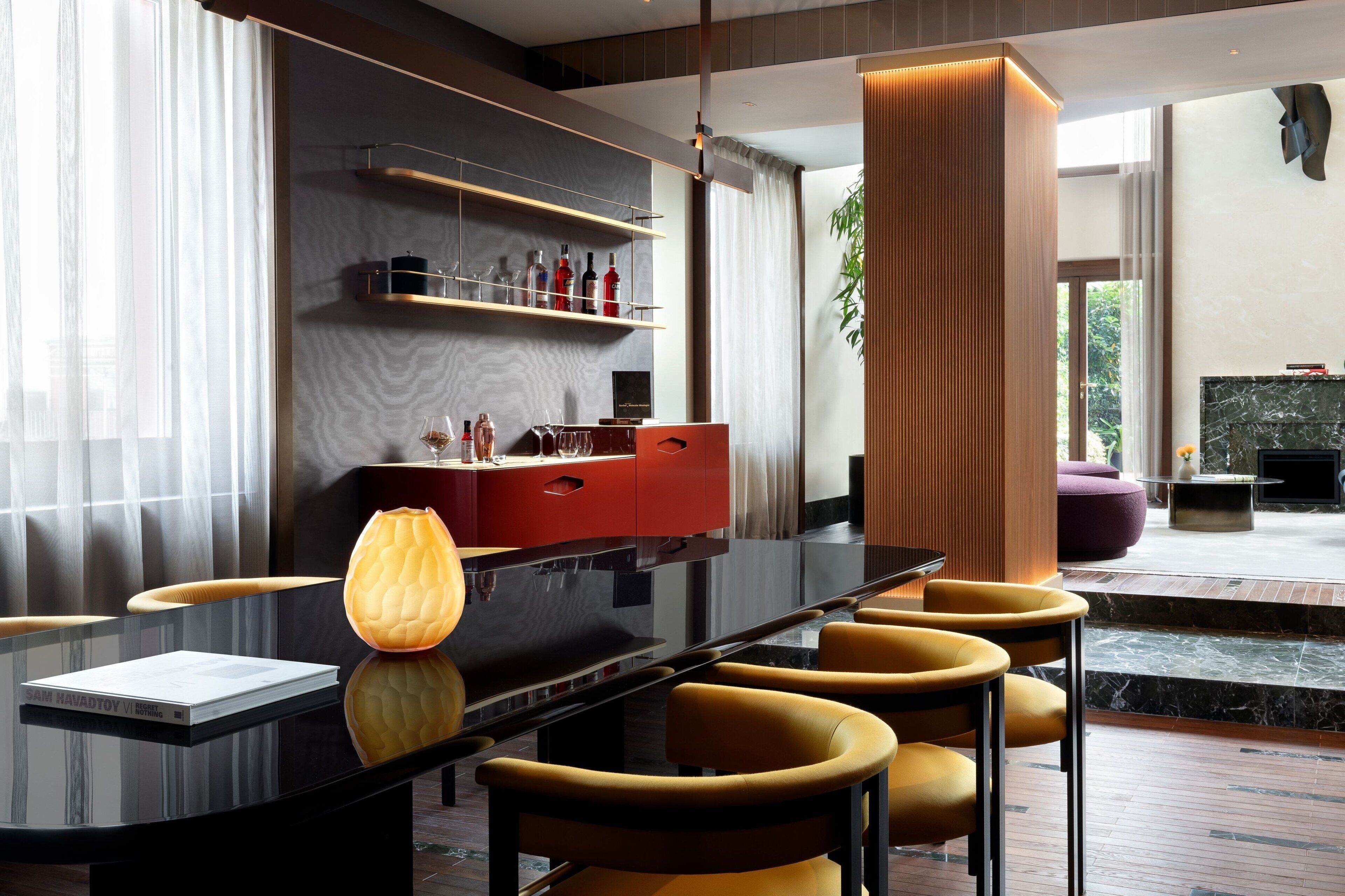 Een moderne eetruimte met een zwarte tafel, gele stoelen en een rode kast.