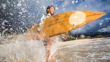 Una persona sosteniendo una tabla de surf con un diseño circular, de pie en el agua con salpicaduras a su alrededor.