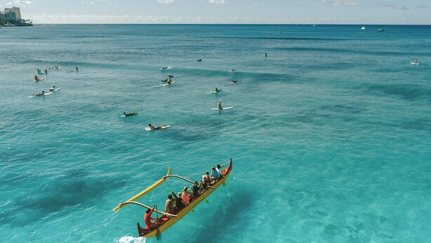 A traditional boat with passengers, sailing on clear turquoise waters.