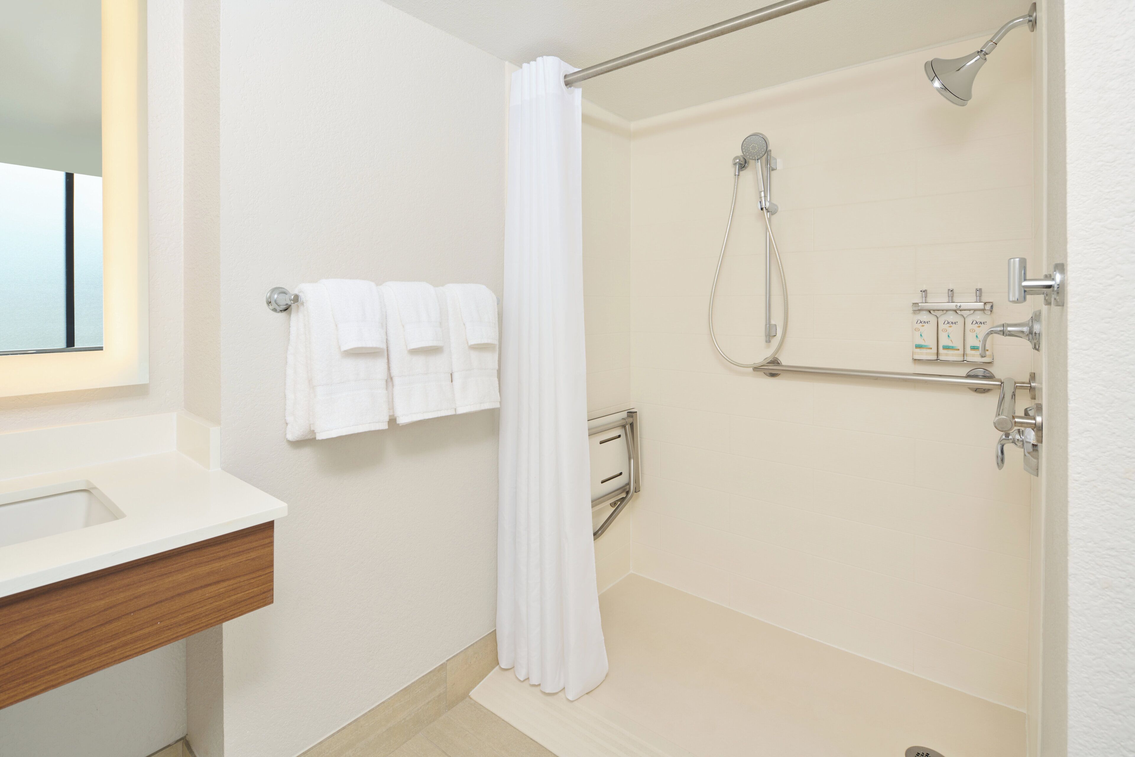 A bathroom with a shower, a toilet, a sink, and a mirror.