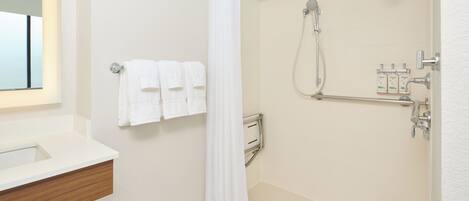 A bathroom with a shower, a toilet, a sink, and a mirror.