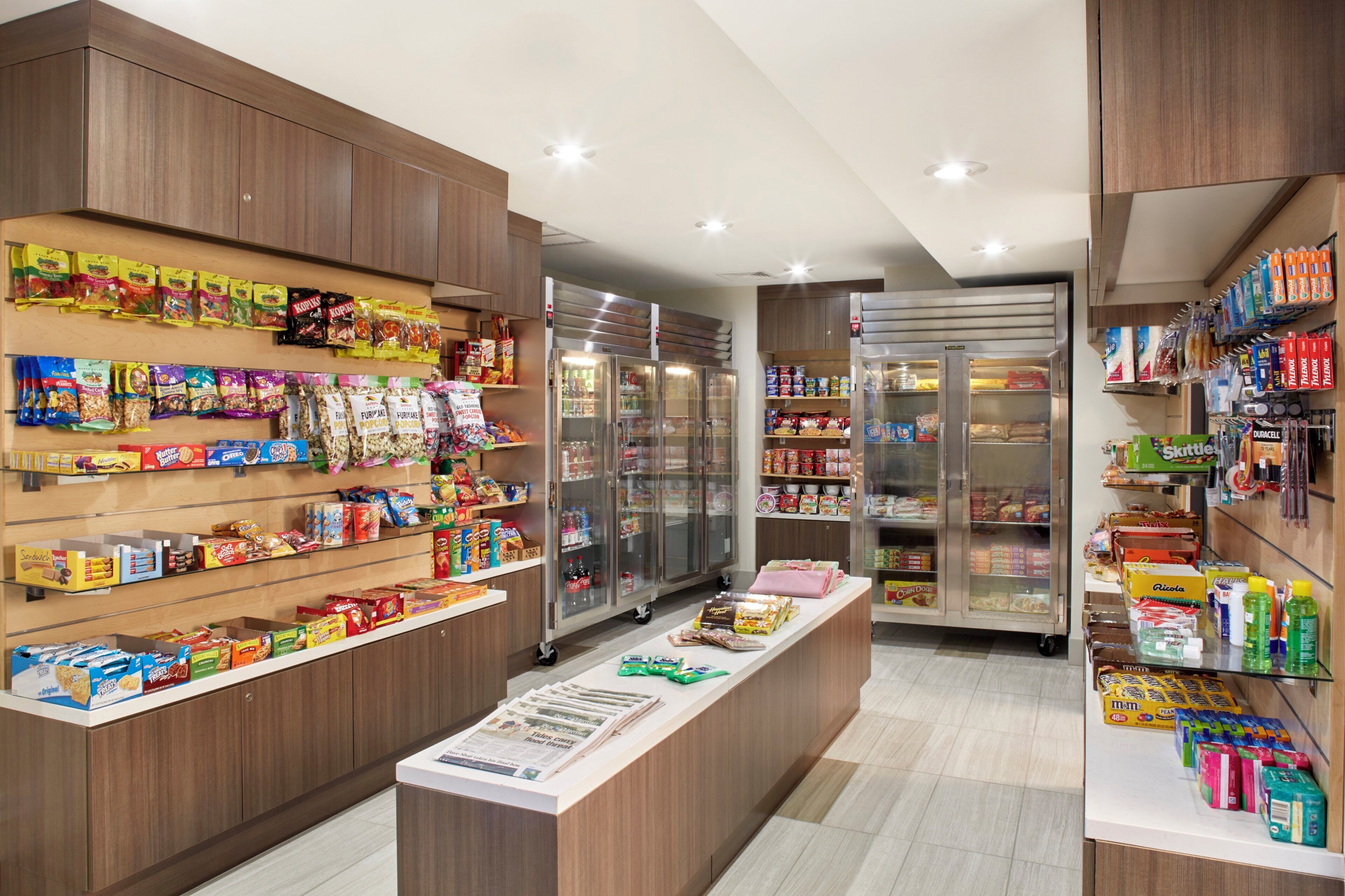Un supermercado con diversos productos alimenticios y bebidas en estantes y secciones refrigeradas.