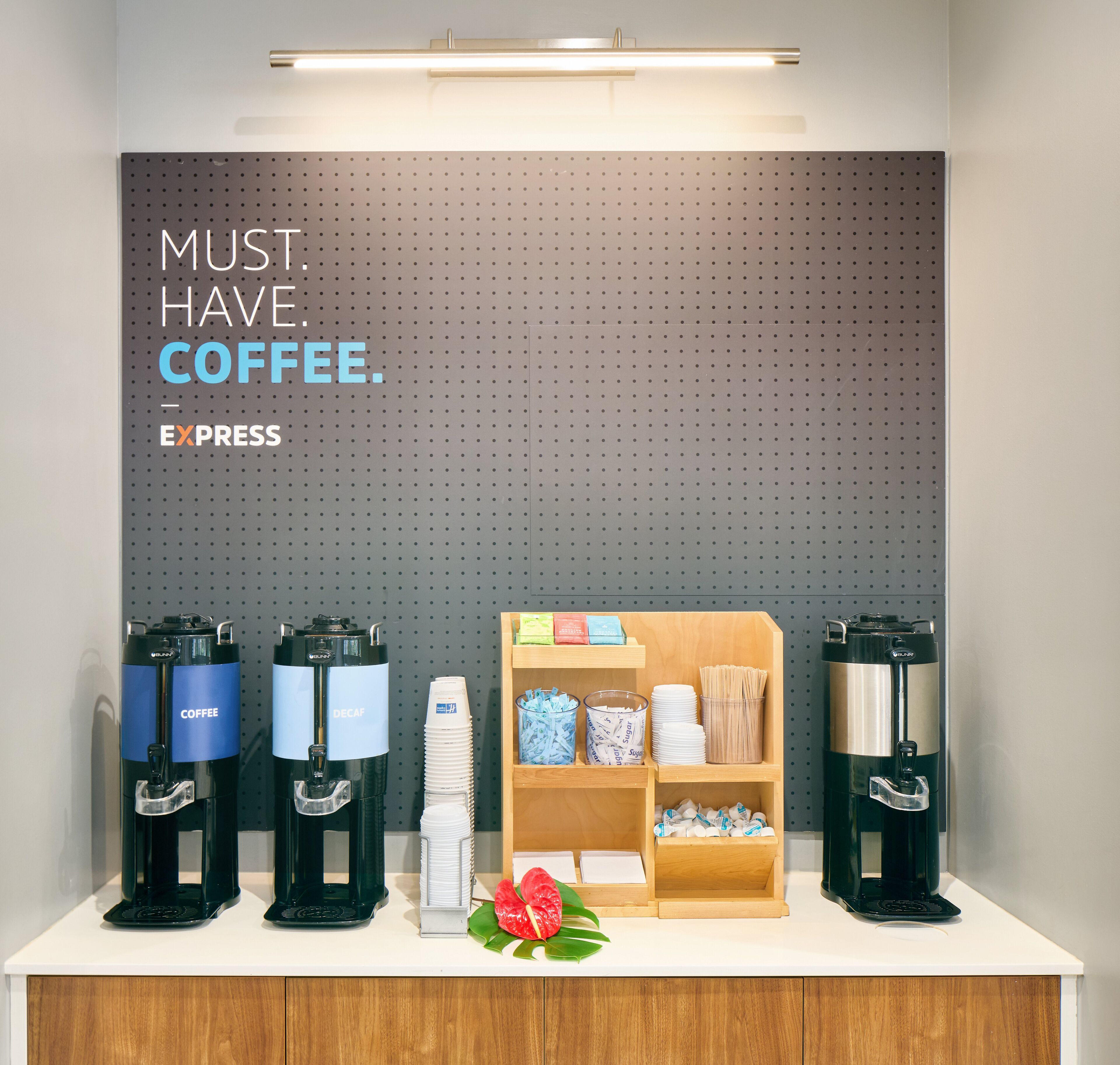 A coffee station with four coffee makers and a sign that reads "MUST. HAVE. COFFEE."