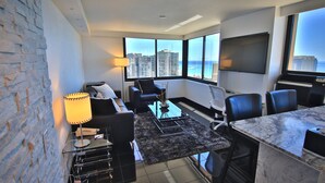 A modern hotel room with a city view, a sofa, a coffee table, and a desk with a chair. - Holiday Inn Express Waikiki by IHG (Honolulu)