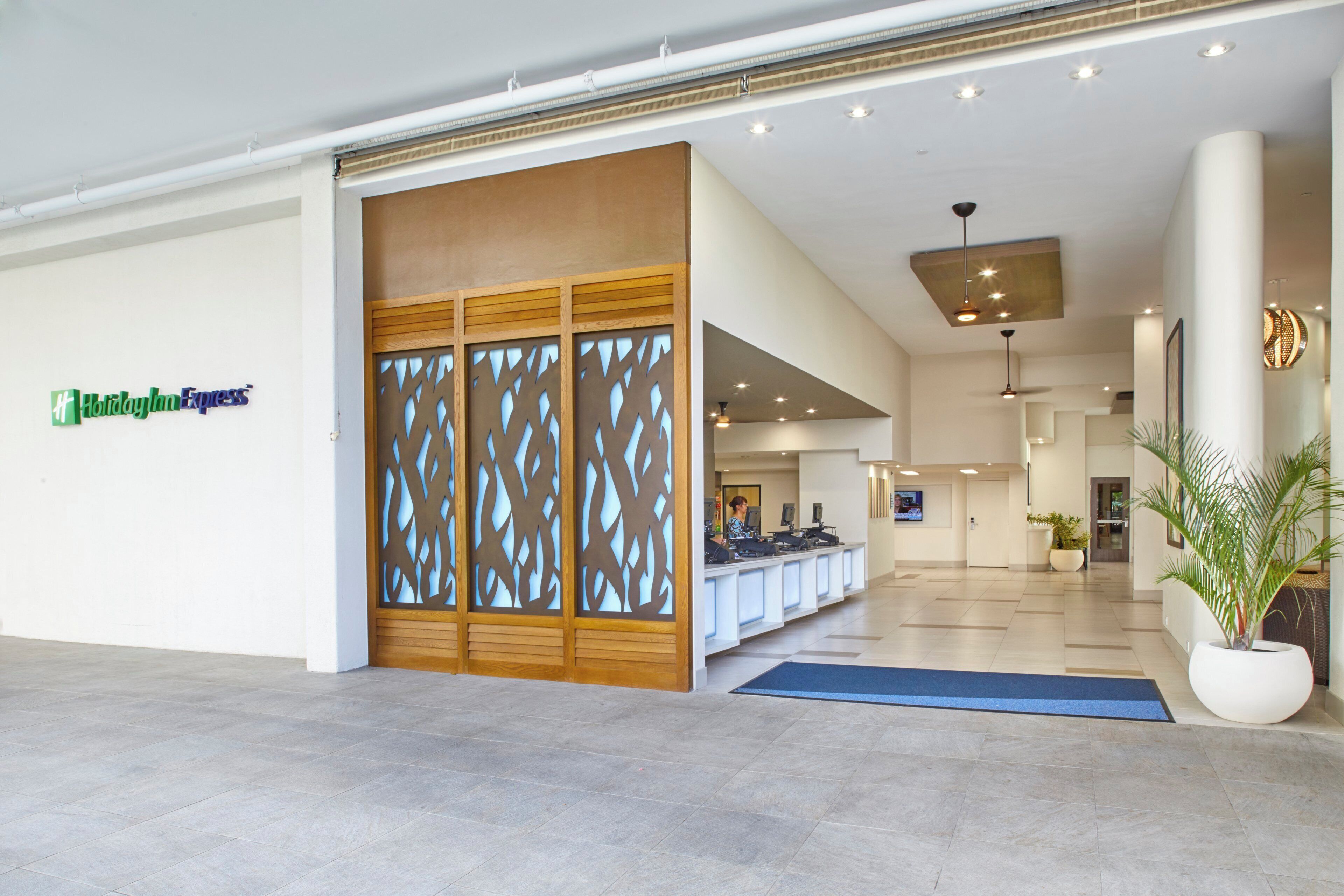 A hotel reception area with a wooden partition, reception desk, and a sign for Holiday Inn Express.