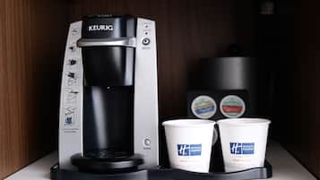 Una cafetera Keurig con dos vasos desechables sobre una encimera blanca.