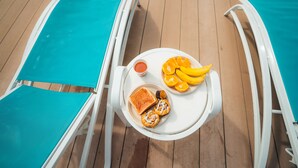A sunbed with a tray containing toast, jam, and a plate of sliced oranges.