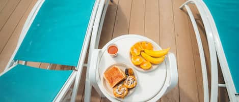 Una tumbona con una bandeja que contiene tostadas, mermelada y un plato de rodajas de naranja.
