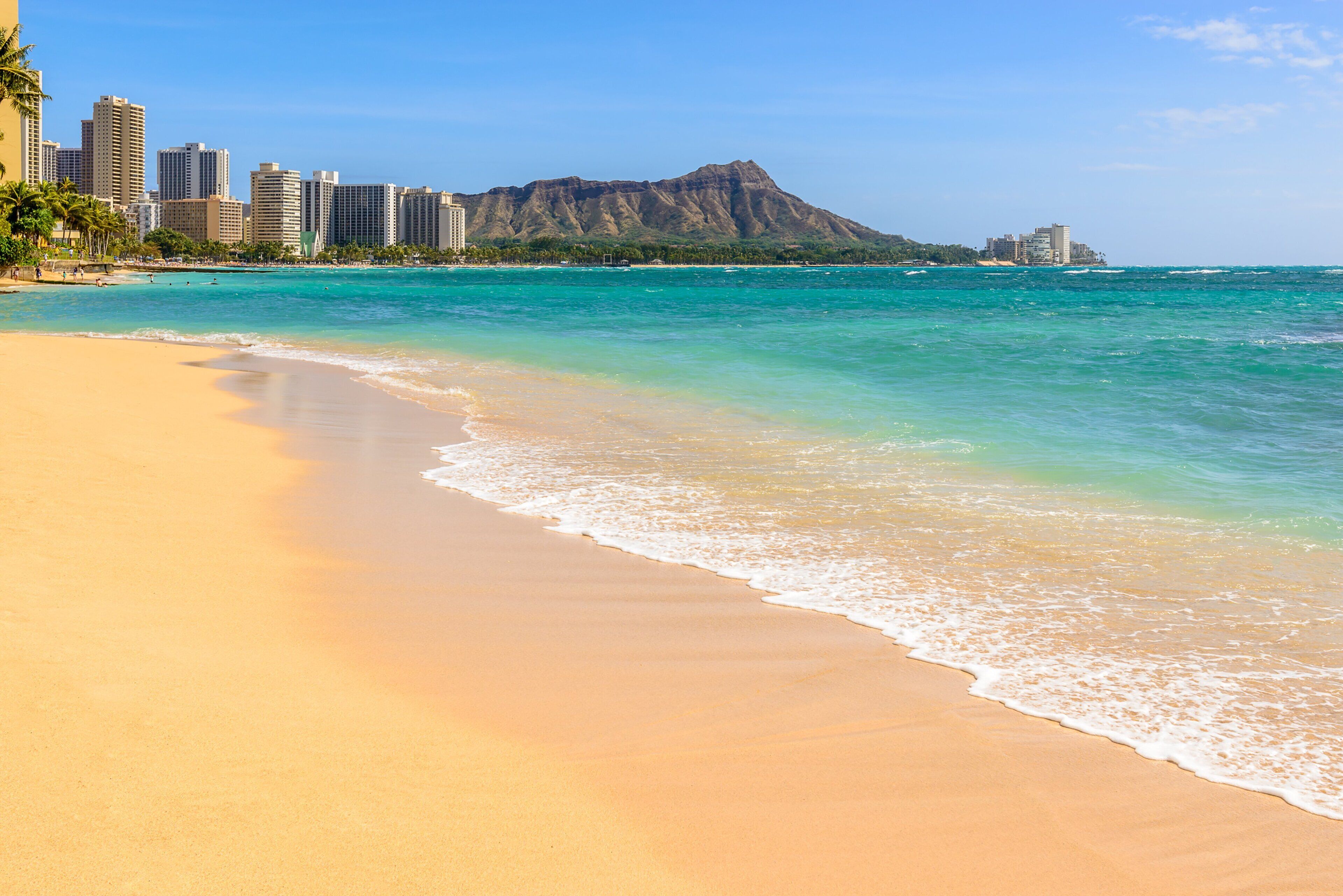 A beach with a mountain in the background and a city skyline.
