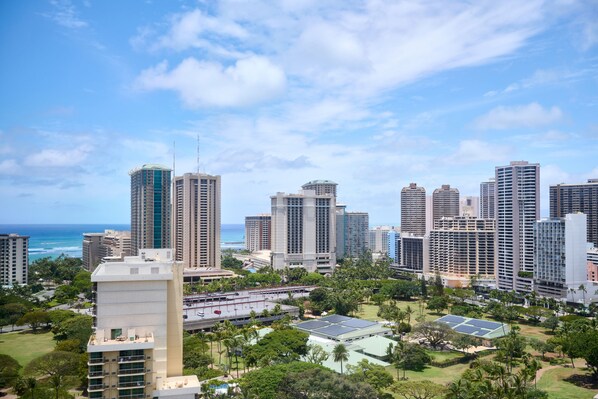 A cityscape with high-rise buildings, a clear sky, and a view of the ocean.