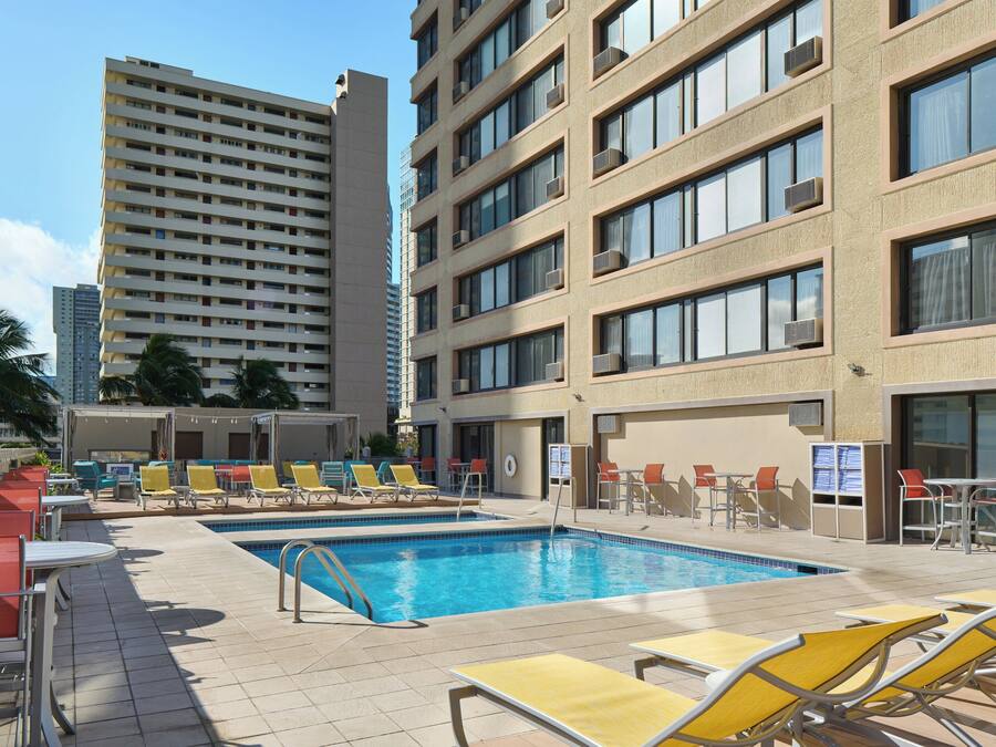 A hotel pool area with multiple lounge chairs and a swimming pool.