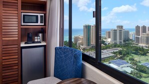 A compact room with a view of a cityscape and the ocean. It includes a microwave, a coffee machine, and a seating area with a view. - Holiday Inn Express Waikiki by IHG (Honolulu)