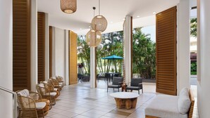 A modern lounge area with wicker chairs, a round wooden coffee table, and a sofa. - Holiday Inn Express Waikiki by IHG (Honolulu)