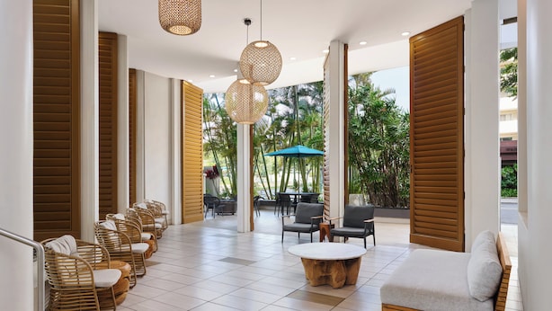 A modern lounge area with wicker chairs, a round wooden coffee table, and a sofa. - Holiday Inn Express Waikiki by IHG (Honolulu)