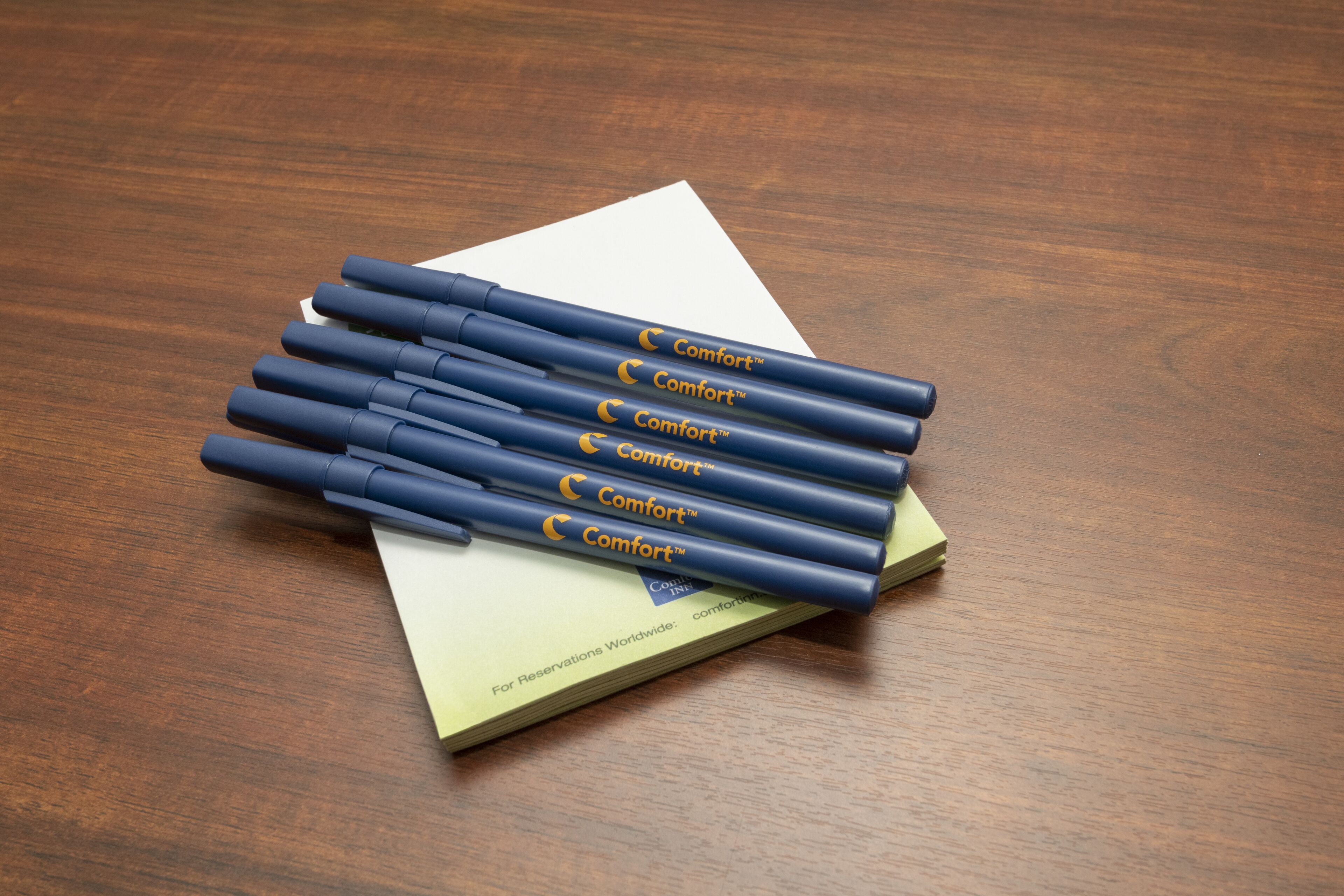 A stack of blue pens with 'Comfort' branding on a wooden surface.