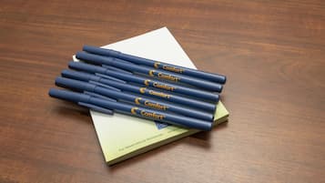 A stack of blue pens with 'Comfort' branding on a wooden surface.