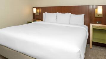 A hotel room with a large bed, two bedside tables, and wall-mounted lamps.