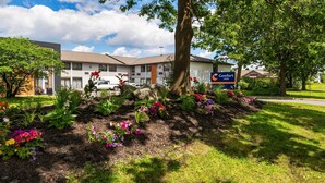 A Comfort Inn hotel with a landscaped garden, a parking lot, and a clear blue sky. - Comfort Inn Kanata Ottawa West (Ottawa)