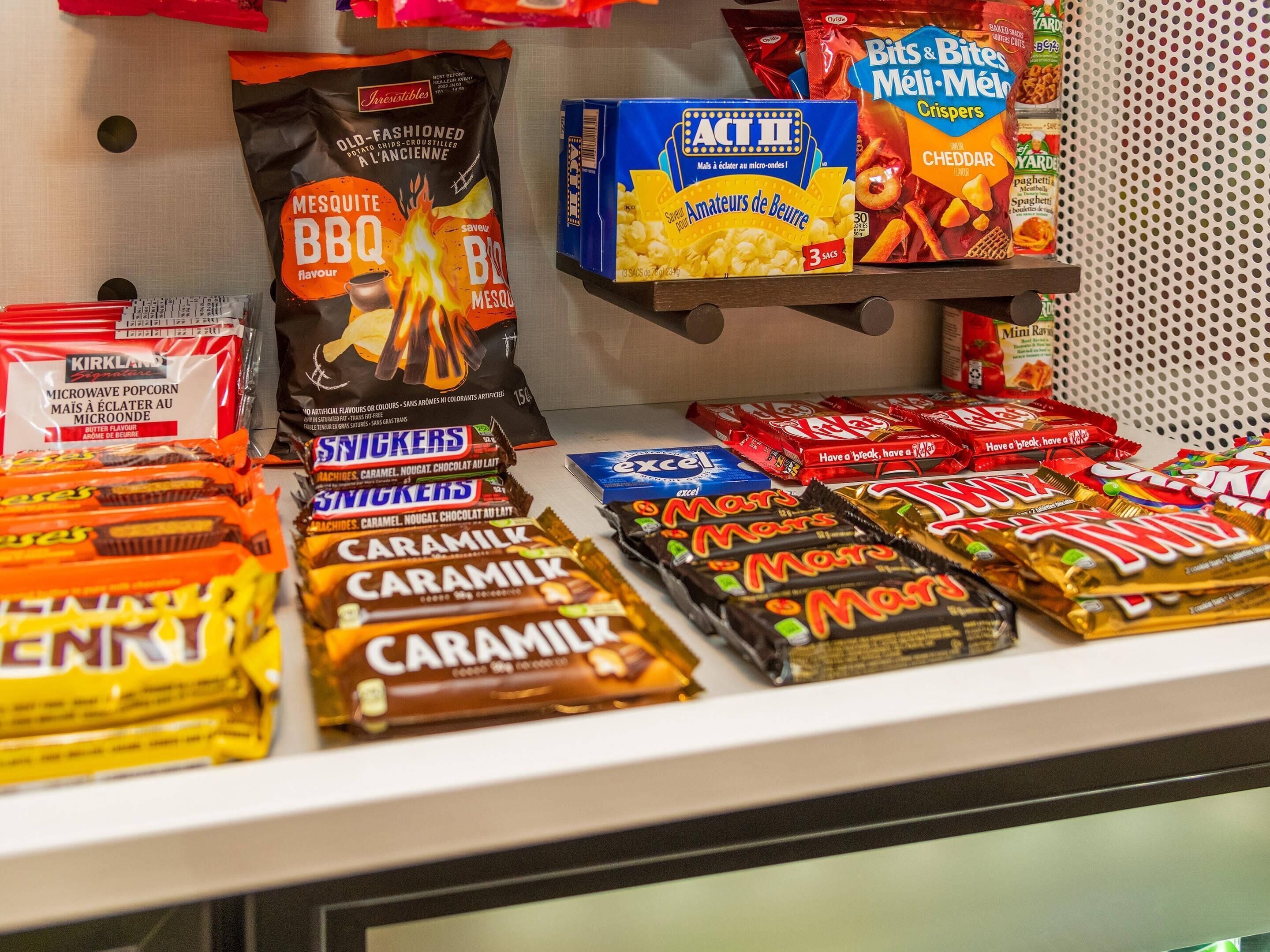 Una exhibición de snacks con varias marcas como Snickers, Mars y Caramilk.