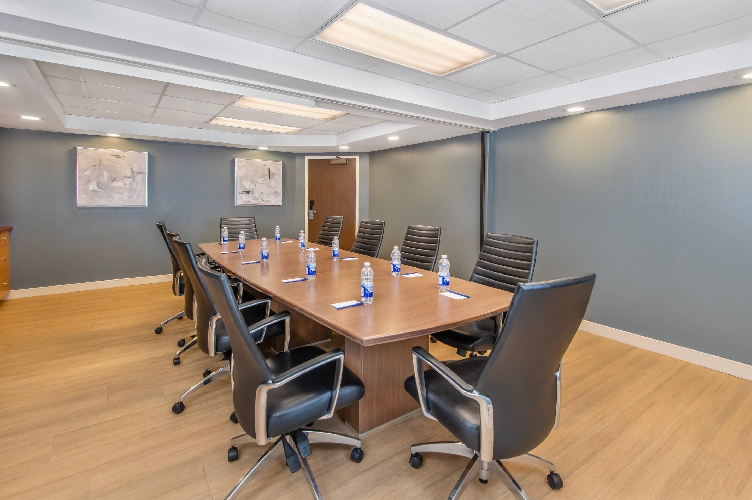 A conference room with a long table, chairs, and water bottles.