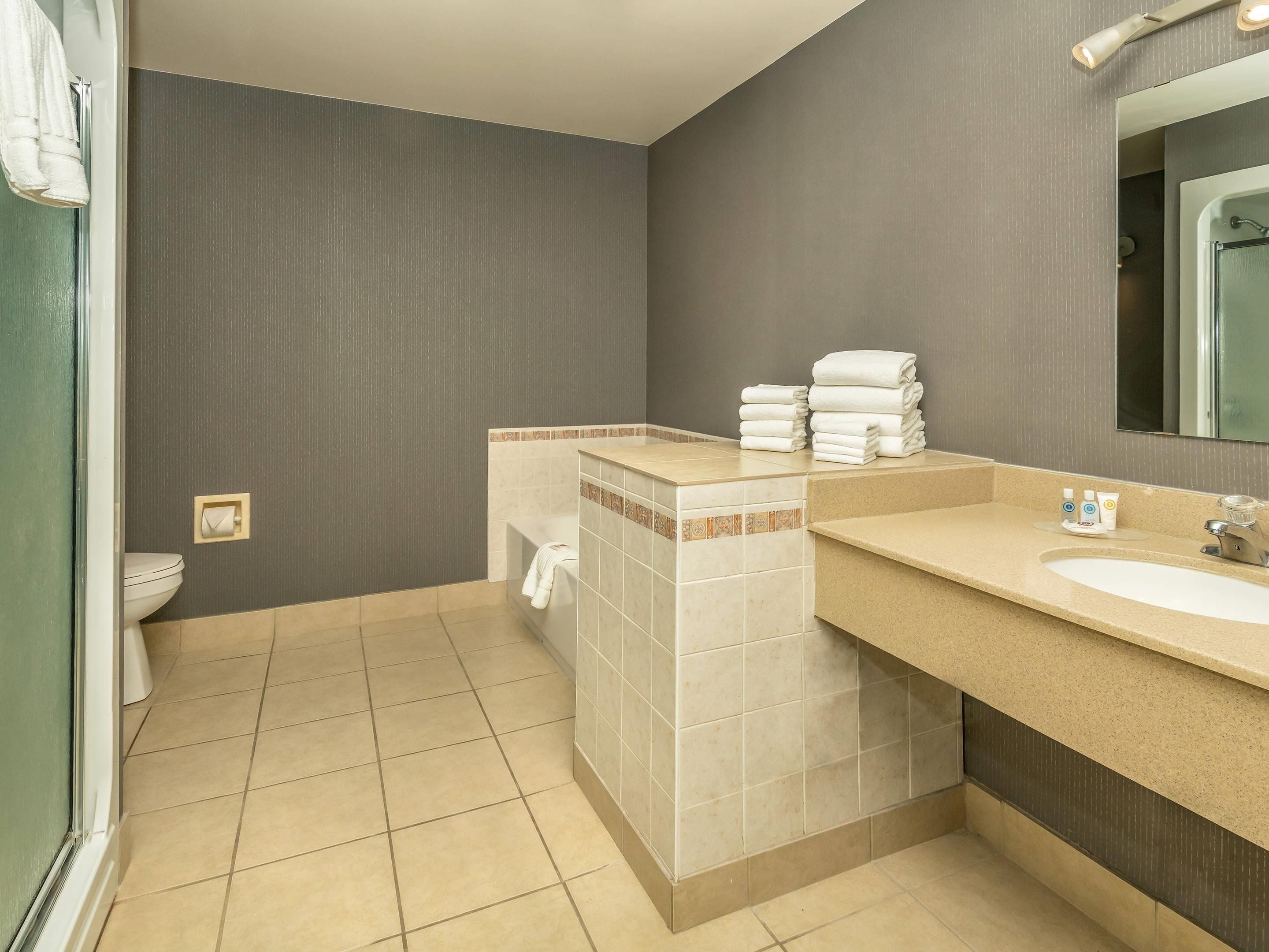 Een moderne badkamer met toilet, wastafel en spiegel.