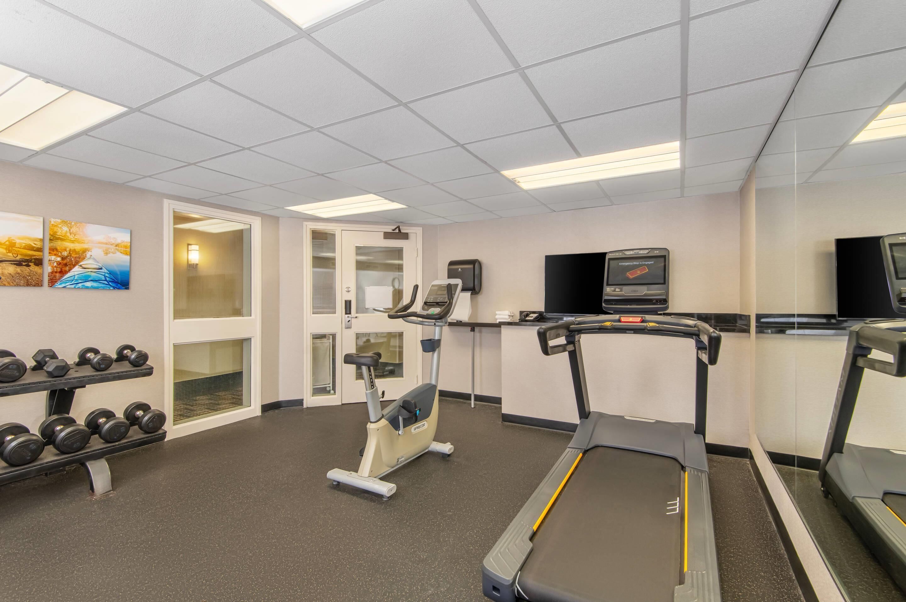 Ett gym med löpband, en crosstrainer och hantlar.