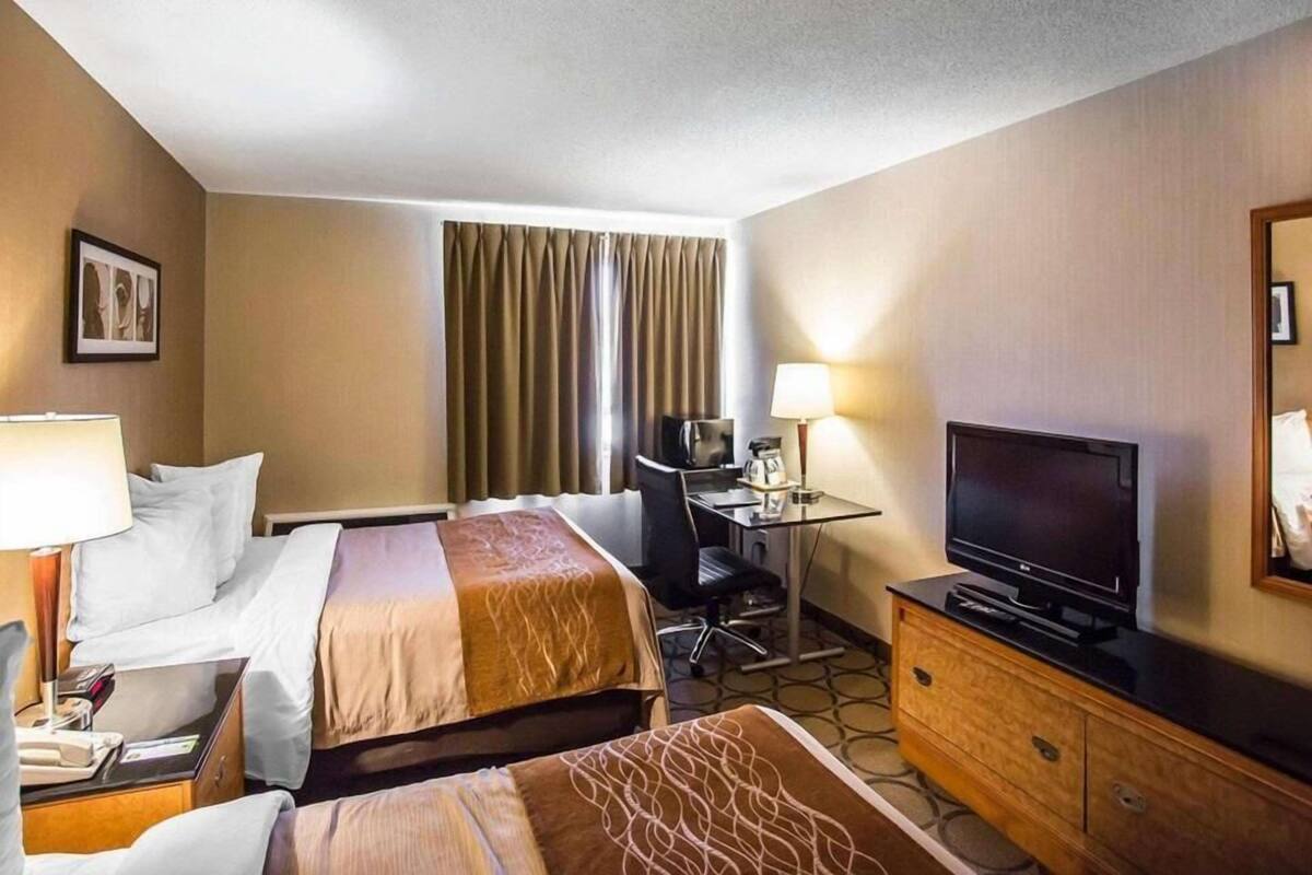 A hotel room with two beds, a desk with a chair, a television, and a dresser.