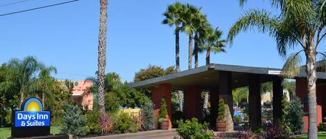 A Days Inn & Suites with a clear sign, palm trees, and a covered outdoor area.