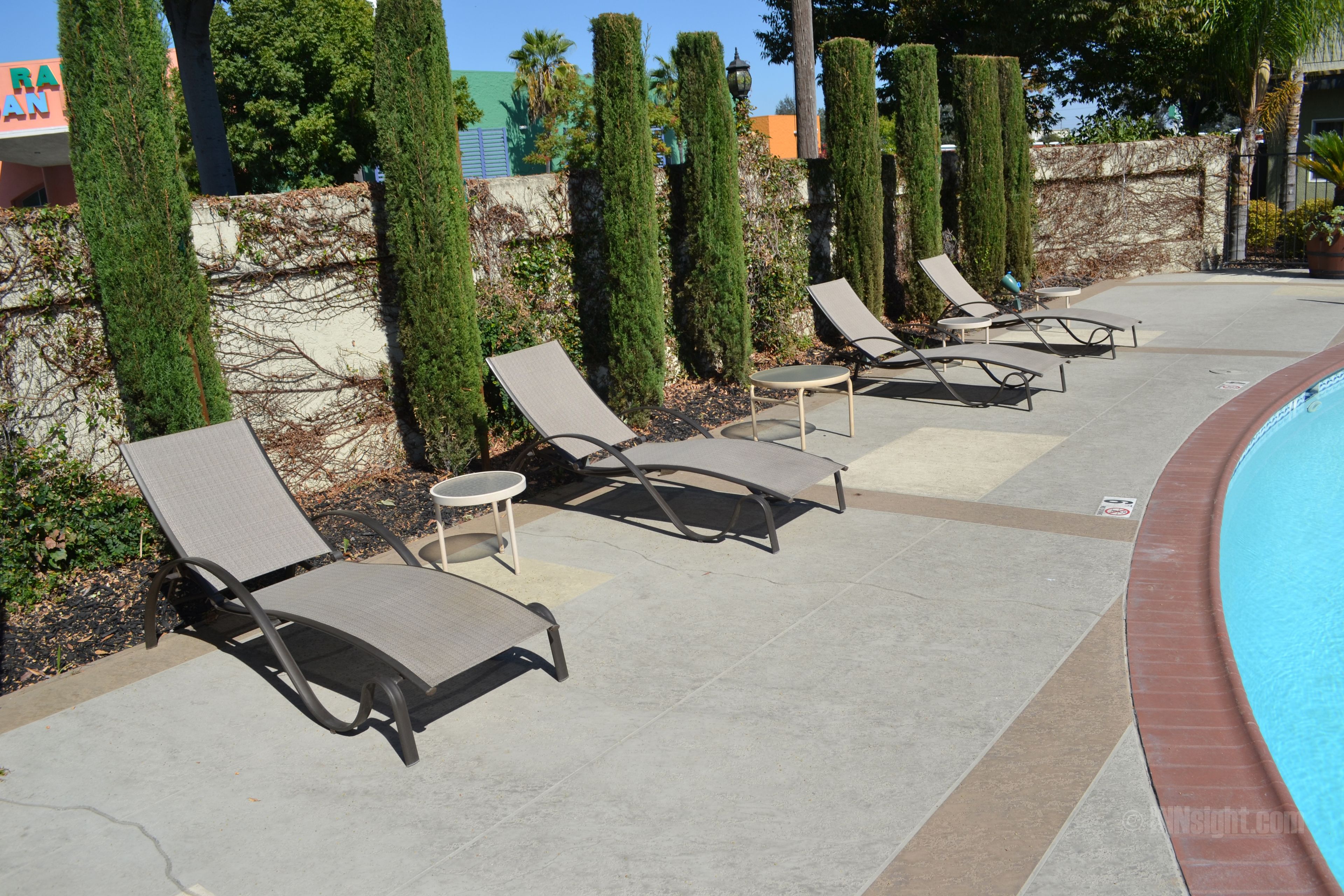 Un área junto a la piscina con sillones de descanso y una piscina.