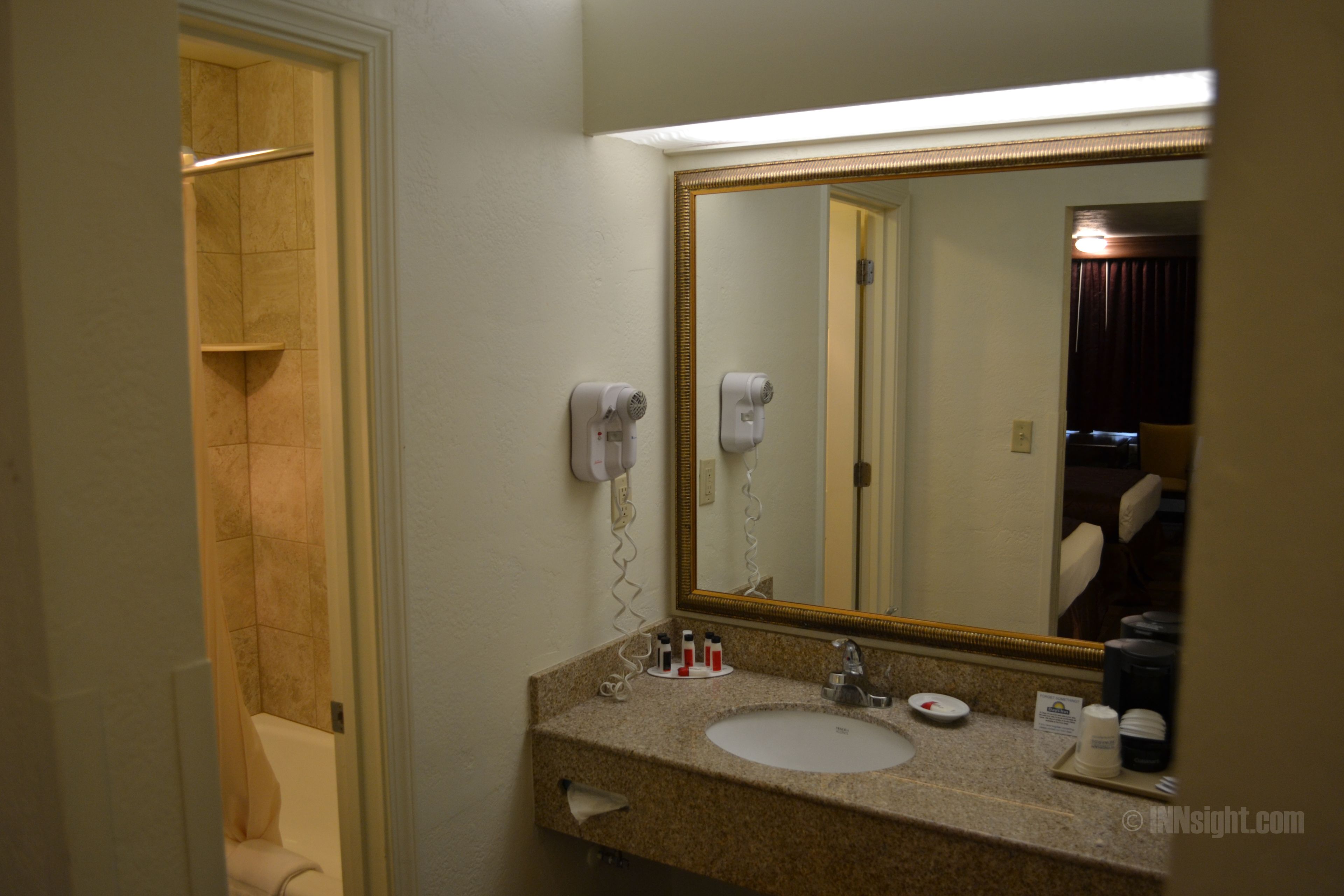 Une salle de bain d’hôtel équipée d’un lavabo, d’un miroir et d’un sèche-cheveux.