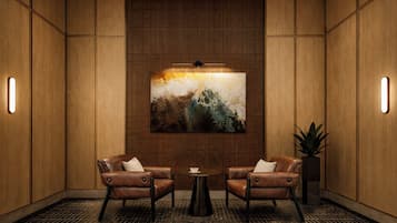 A room with two leather armchairs, a small round table, and a large abstract painting on the wall.