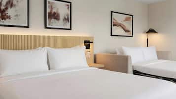 A hotel room with two beds, a headboard, and artwork on the walls.