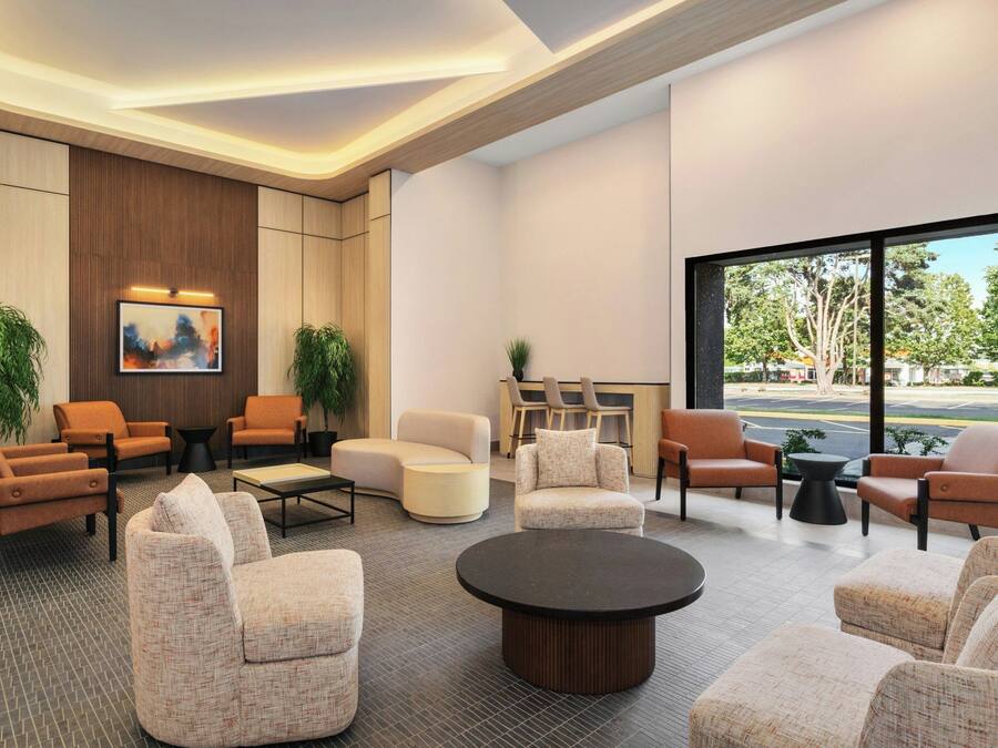 Eine moderne Lobby mit Sitzgelegenheiten, einem Couchtisch und einem großen Fenster mit Blick ins Freie.