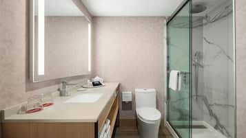 A modern bathroom with a glass shower enclosure, a dual sink vanity, and a toilet.