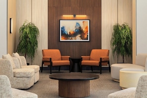 A lobby with two orange armchairs, a round coffee table, and a large abstract painting on the wall. - Red Roof Inn PLUS+ Vancouver Airport (Richmond)