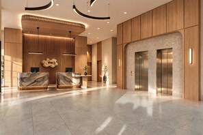 Un área de recepción moderna con mostradores de mármol, paneles de madera y una lámpara central.