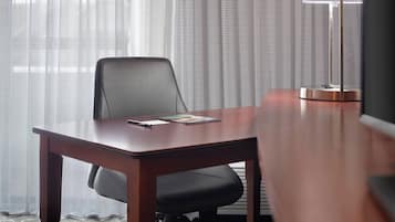 A conference table with a chair, a lamp, and a magazine on the table.