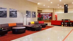A modern lobby with a sectional sofa, round ottomans, and a red reception desk.