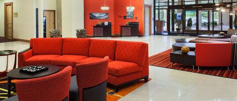 A modern lobby with a red sofa, black chairs, and a reception desk.