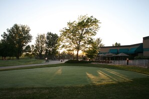 A well-maintained grassy area with a walking path, trees, and a building with a green roof. - Doubletree Hotel Grand Junction (Grand Junction)