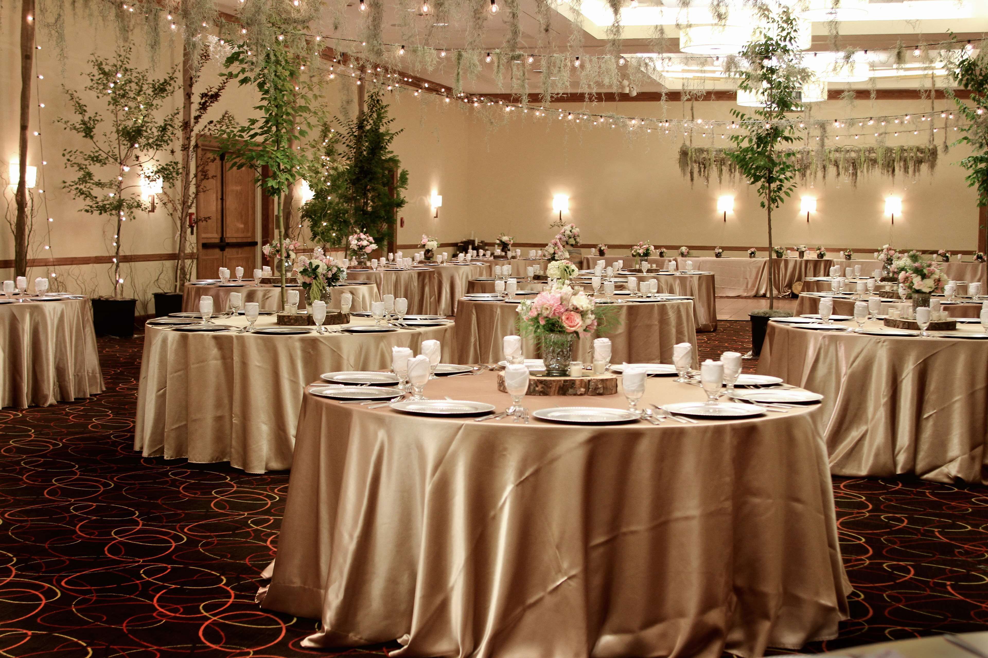 A banquet hall with round tables set for dining, featuring elegant table settings and floral centerpieces.
